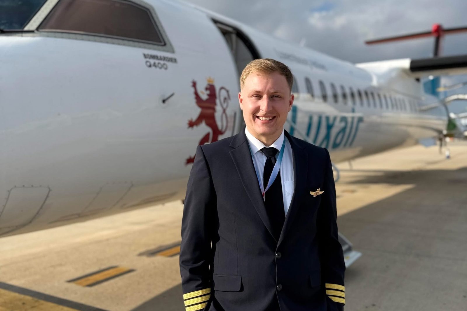 Tommy Scohy in uniform in front of a Luxair Dash 8 Q400